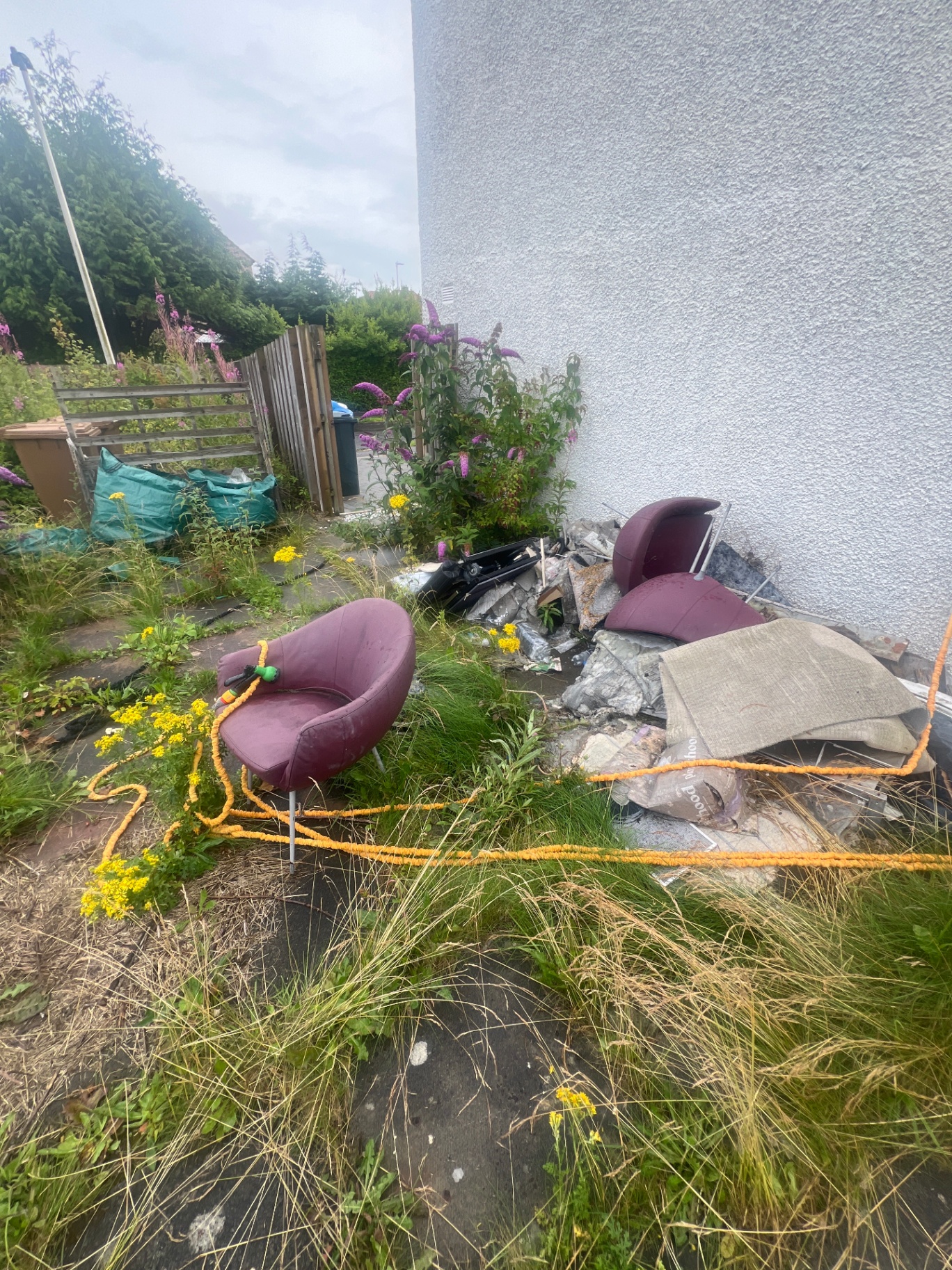Before shot of a garden makeover project in Kirkliston and South Queensferry, EH30, featuring overgrown grass, dumped furniture and rubble.