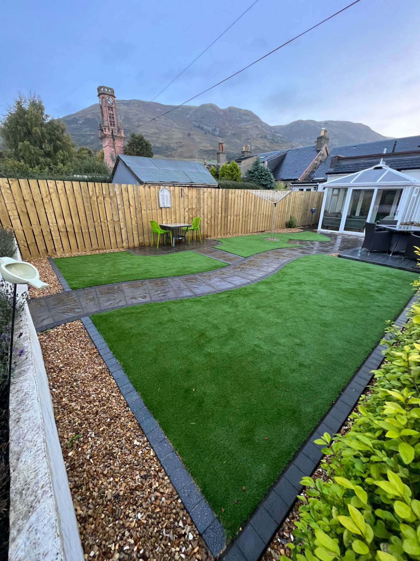 Vibrant artificial grass lawn installation in Winchburgh garden with professional edging and natural stone border