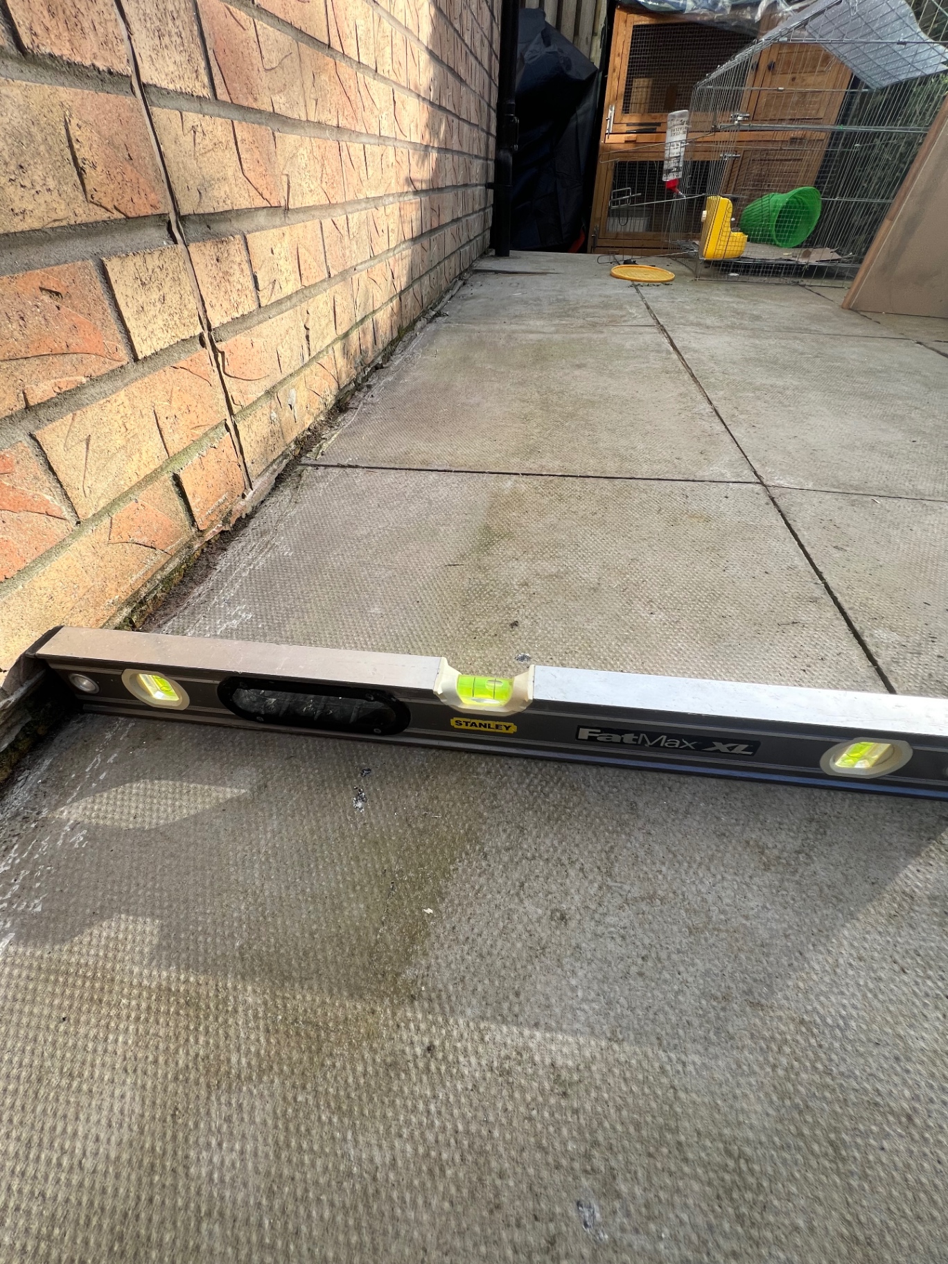 Spirit level revealing incorrect patio gradient toward property in Falkirk - drainage fault inspection