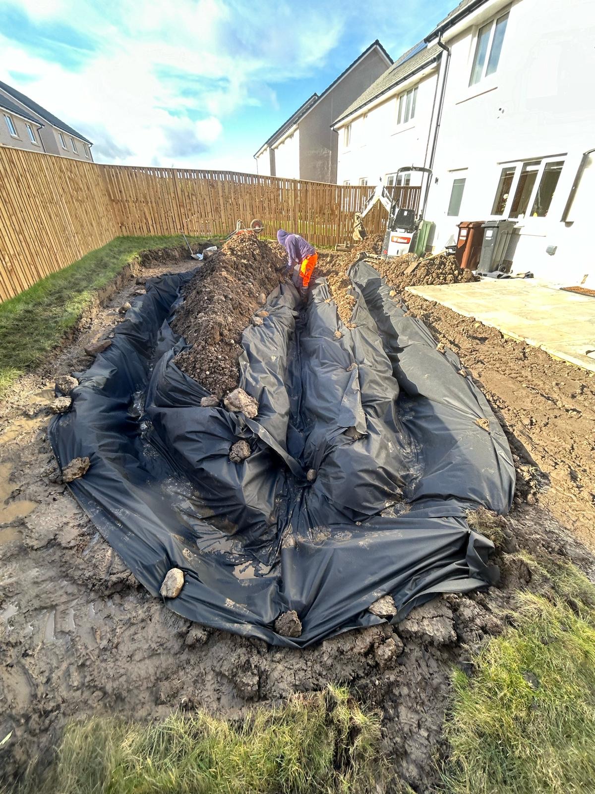 Garden drainage installation in progress showing proper sub-base preparation on clay soil with geotextile membrane