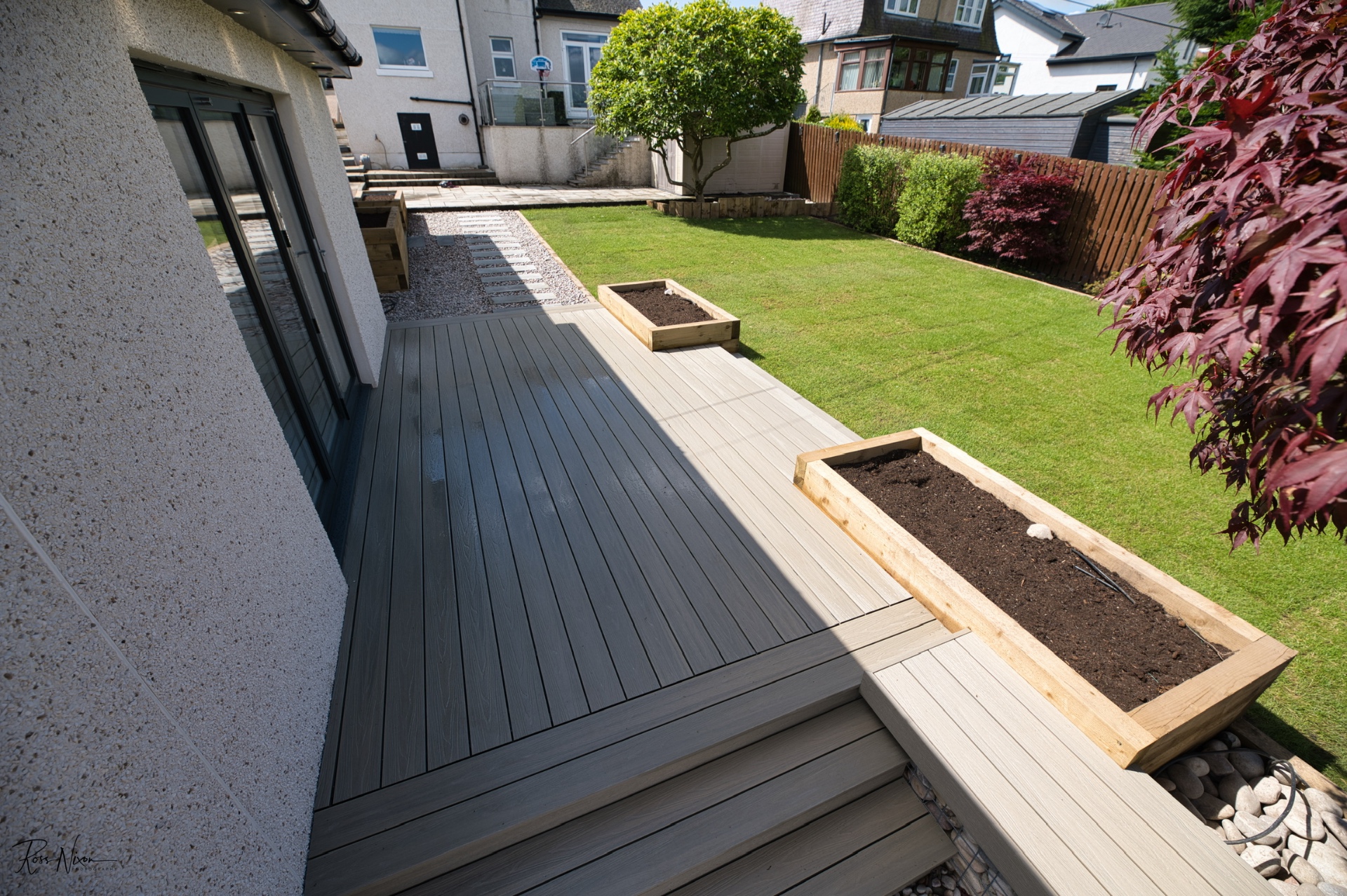 Multi-level composite decking with timber sleeper raised bed walls in Edinburgh garden