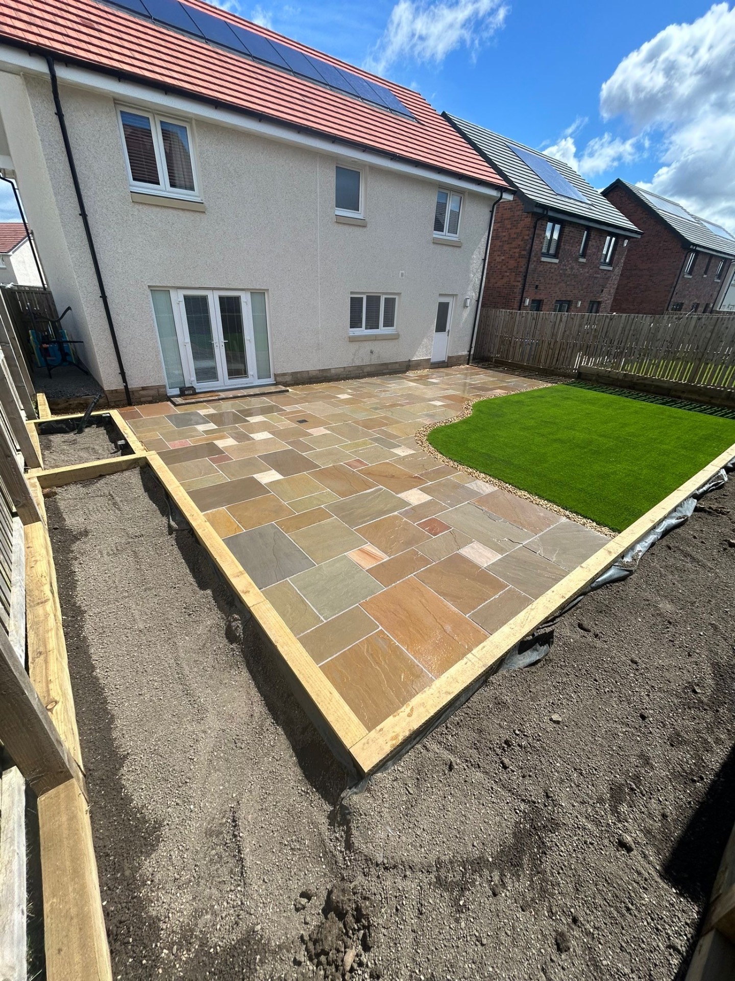 Professional artificial grass installation in Kirkliston EH29 garden showing expert sub-base preparation, proper edging, and drainage system installation by Maybury Landscaping