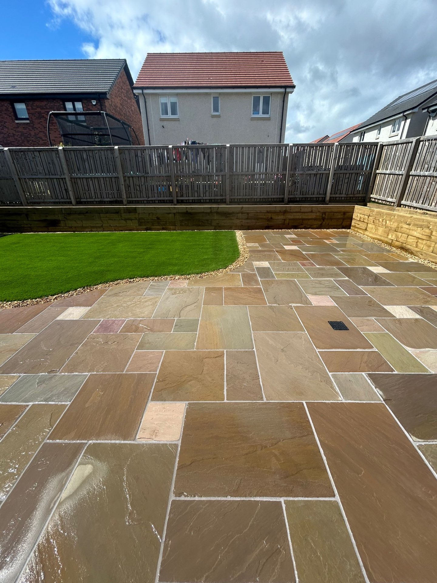 Final completion view of Winchburgh garden transformation with patio, grass, and raised beds