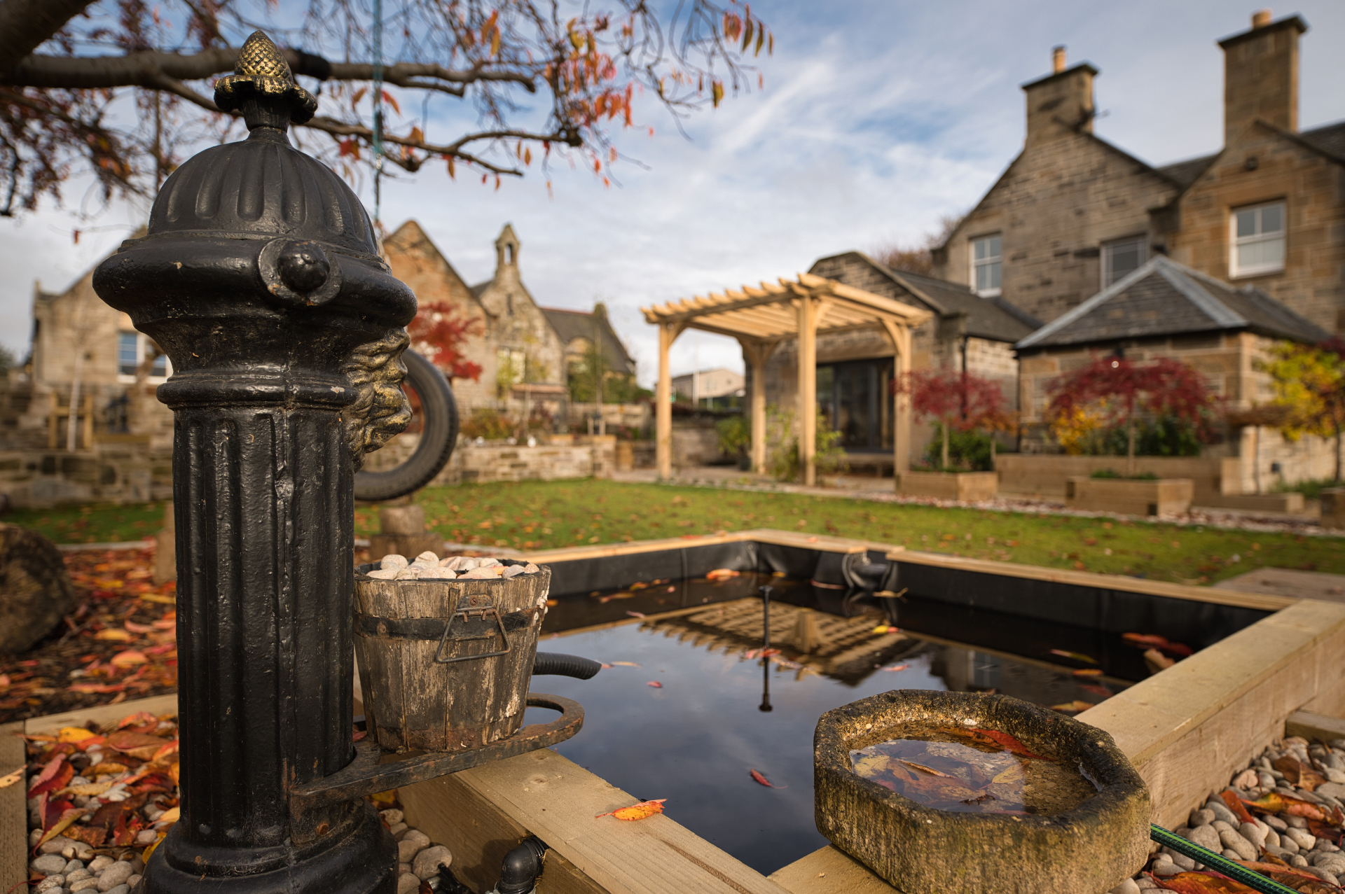 Natural stone water feature in Winchburgh garden with cascading water, surrounding plants and sandstone paving edge
