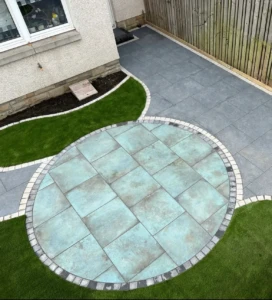 "Maybury Landscaping transformed this Ratho garden with a low-maintenance design featuring Caledonian stone verdigris porcelain paving, Sargent black paving, and artificial grass."