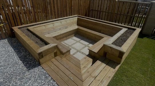 A sunken area with porcelain tile surrounded by timber seating area and plant beds, installed in Dunfermline. Turf also installed.